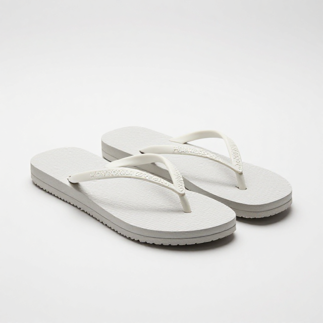 Fotografia de produto em estúdio com fundo branco infinito, um par de chinelos Havaianas Top Feminino na cor branca, ângulo de 3/4, luz natural suave criando sombras delicadas. Sem texto na imagem, apenas visual.