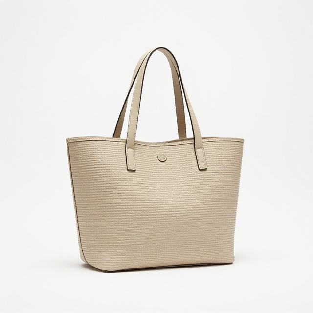 Fotografia de produto em estúdio com fundo branco infinito, uma bolsa de praia Havaianas na cor bege areia, ângulo de 45 graus, mostrando as alças longas e o logo bordado. Sem texto na imagem, apenas visual.